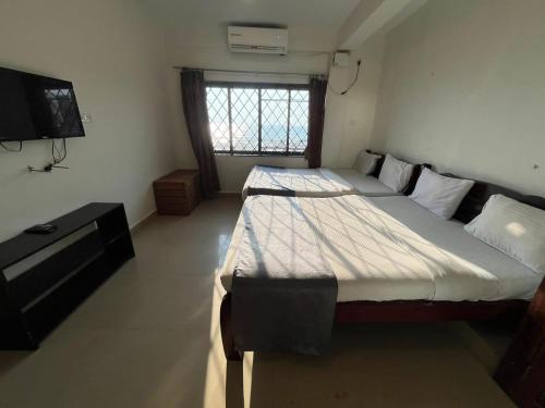 a bedroom with two beds and a television in it at Baga Beach Sunset in Baga