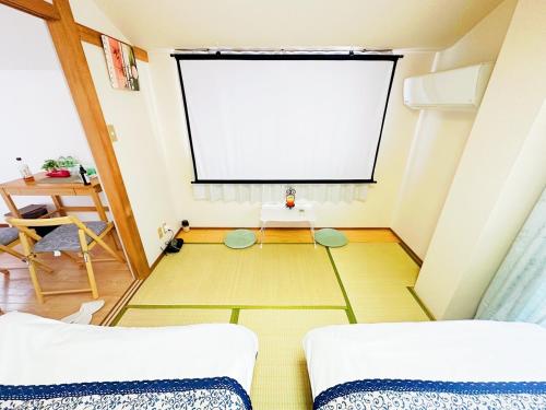 a room with two beds and a projection screen at メゾンドリバージュ205 in Tokyo