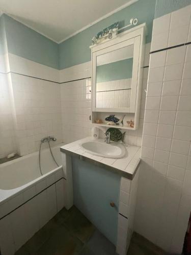 une salle de bain avec un lavabo, un miroir et une baignoire dans l'établissement Sur le port face à la citadelle, à Bonifacio