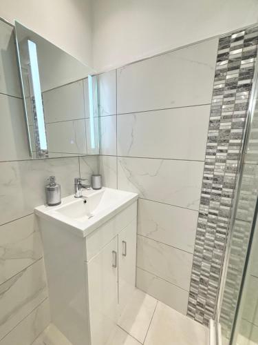 a white bathroom with a sink and a shower at Cosy Modern Flat with garden in Longbridge