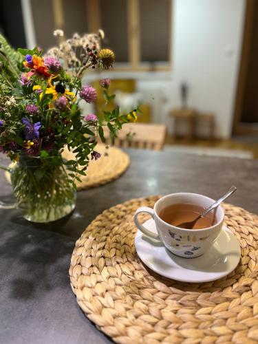 a cup of coffee on a table with a vase of flowers at Slunečný apartmán in Cerny Dul