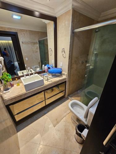a bathroom with a sink and a toilet and a mirror at Tropical Executive Flat Vista da Orla in Manaus