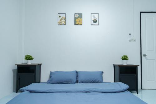 ein Schlafzimmer mit einem Bett mit blauen Laken und zwei Tischen in der Unterkunft ME House Banchang in Ban Chang