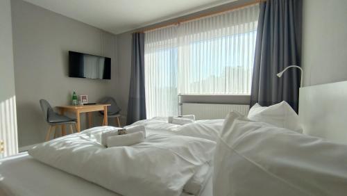 two white beds in a hotel room with a window at Ostseehotel Kappeln by team SchleiFee in Kappeln