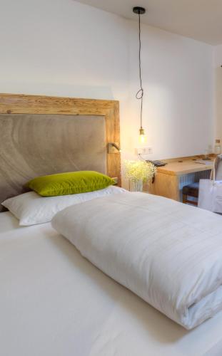 a large white bed with a green pillow on it at Designhotel Sonnhof by Vitus Winkler in Sankt Veit im Pongau