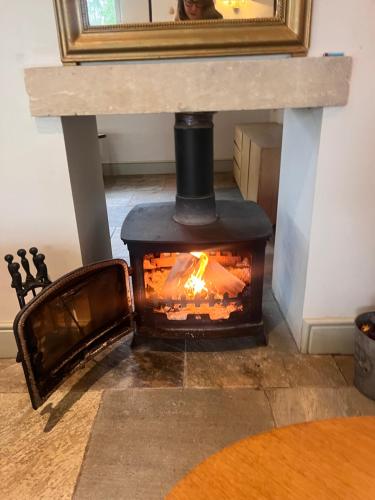 a wood stove in a room with a table at Elmcroft, Large House with Shepherds Hut in Gillingham