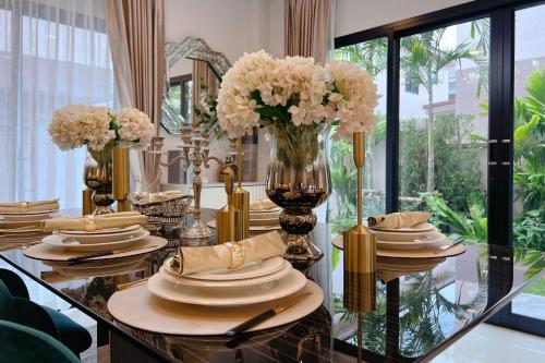 a dining table with plates and flowers on it at 超值优选 新房特惠 独栋泳池花园别墅 15分钟到海边 in Ban Huai Yai