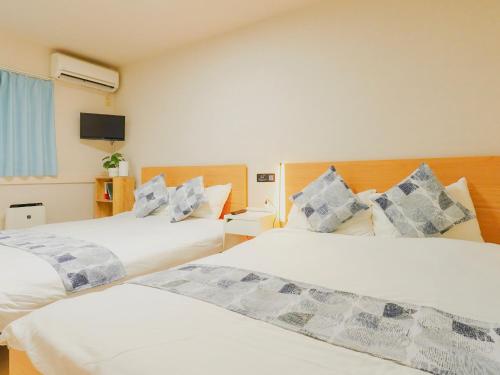 a bedroom with two beds and a flat screen tv at 星野の宿 日本橋黒門道頓堀心斎橋難波エリア中心地 in Osaka
