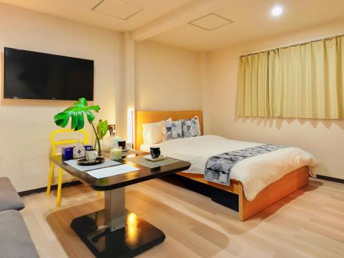 a bedroom with a bed and a desk and a tv at 星野の宿 日本橋黒門道頓堀心斎橋難波エリア中心地 in Osaka