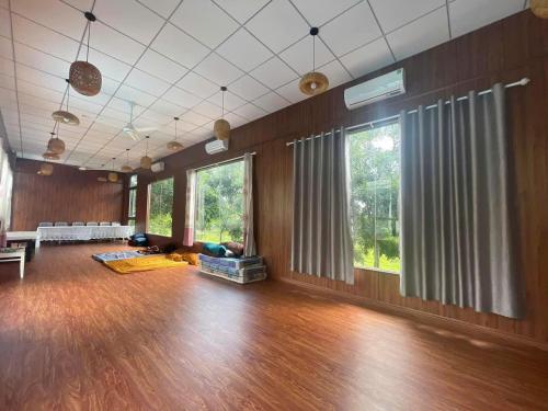 a large living room with wooden floors and windows at Nhà Bên Đồi - The Hill House in La Sơn