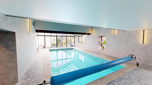 a large swimming pool in a building at Les Grands Ormeaux - Elégance & Piscine chauffée - L'Instant Clef in Joué-en-Charnie