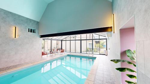 a swimming pool in a house with a large window at Les Grands Ormeaux - Elégance & Piscine chauffée - L'Instant Clef in Joué-en-Charnie