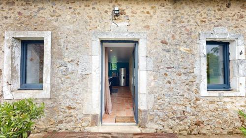 a stone building with two windows and a doorway at Les Grands Ormeaux - Elégance & Piscine chauffée - L'Instant Clef in Joué-en-Charnie