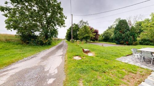 a dirt road with a table and chairs in a field at Les Grands Ormeaux - Elégance & Piscine chauffée - L'Instant Clef in Joué-en-Charnie