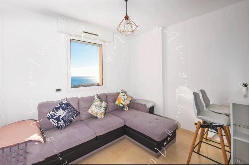 - un salon avec un canapé violet et une fenêtre dans l'établissement Vu la mer de Monaco, à Beausoleil