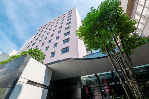 a tall building with a palm tree in front of it at Richmond Hotel Kagoshima Tenmonkan in Kagoshima