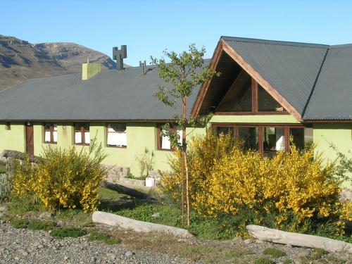 ein gelbes Haus mit schwarzem Dach in der Unterkunft Bla Lodge in El Calafate