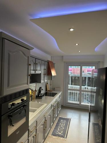 une grande cuisine avec un évier et une grande fenêtre dans l'établissement Appartement luxe Chateaucreux, à Saint-Étienne