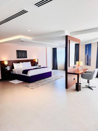 a bedroom with a bed and a table and a desk at Kyriad Hotel Salalah in Salalah