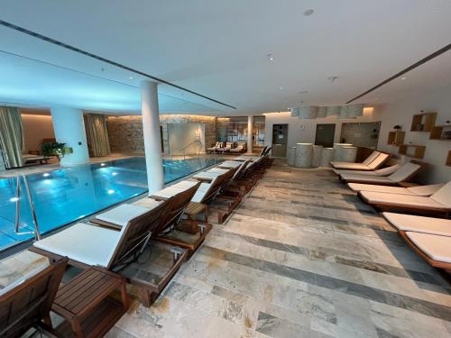 a pool with a row of chairs and a swimming pool at Alpine Luxury Apartment Davos with Spa Access to 5 Star Hotel in Davos