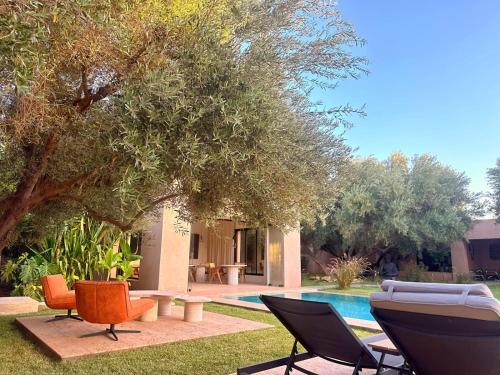 a yard with chairs and a swimming pool at Jardin Sakina - Chambre d'hôtes in Marrakech