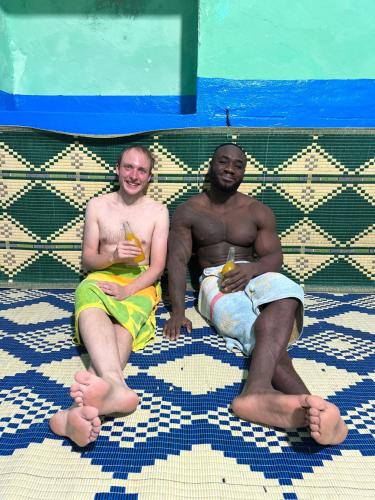 two men sitting on the floor with drinks at Dar Hkaïem in Hammam Sousse