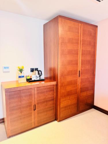 a wooden cabinet with a coffee maker on top of it at Kyriad Hotel Salalah in Salalah