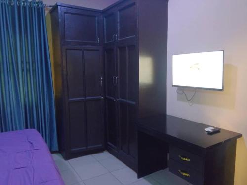 a bedroom with a desk and a tv on a wall at 2 Bed-Sleeps 4-Free Parking-AirCon in Benin City