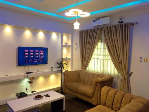 a living room with a couch and a tv at 2 Bed-Sleeps 4-Free Parking-AirCon in Benin City