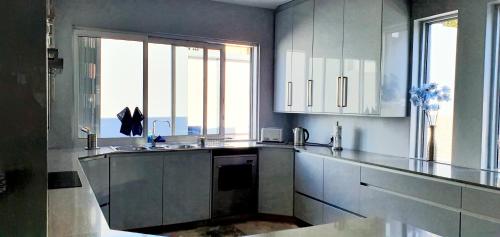 a kitchen with white cabinets and a large window at Marble Blue in Cape Town