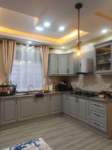 a large kitchen with white cabinets and a window at Serene Homes 01 in Kampala