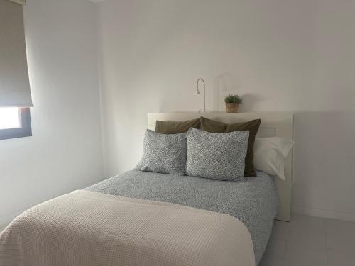 a white bedroom with a bed with six pillows at CASA MESANA Nuevo cama King size en playa con AIRE ACONDICIONADO in Playa Honda