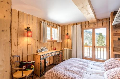 - une chambre avec des murs en bois, un lit et une fenêtre dans l'établissement Montjoie, aux Contamines-Montjoie