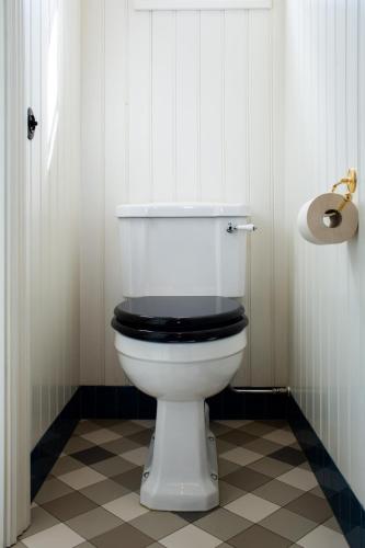 a bathroom with a white toilet with a black seat at STF Villa Söderåsen B&B in Röstånga