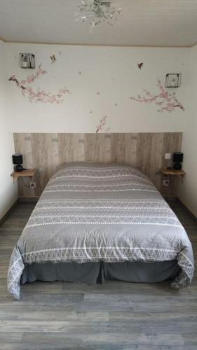 a bedroom with a bed with a gray and white comforter at Gîte la tourterelle in Rancy