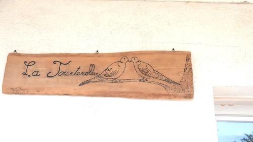 two birds sitting on a wooden sign on a wall at Gîte la tourterelle in Rancy