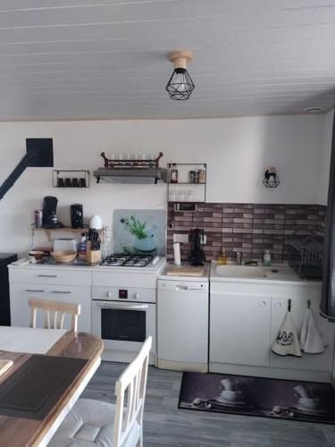 a kitchen with white appliances and a table in it at Gîte la tourterelle in Rancy