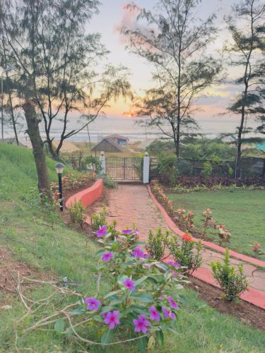 a brick walkway with flowers in a garden at TT Beach Cottages in Candolim