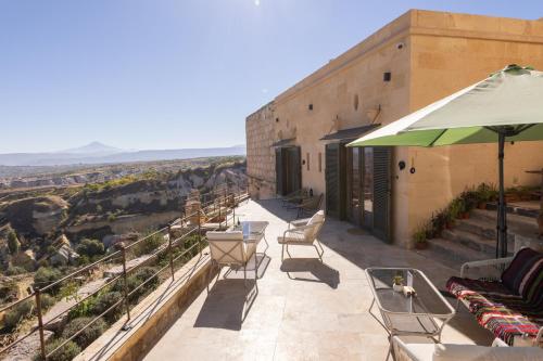 a patio with chairs and tables and an umbrella at Very Peri Cappadocia - The Lifestyle Luxury Design Hotel in Uchisar