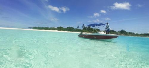 a man standing on a boat in the ocean at Liberty Guesthouse Maldives in Mahibadhoo