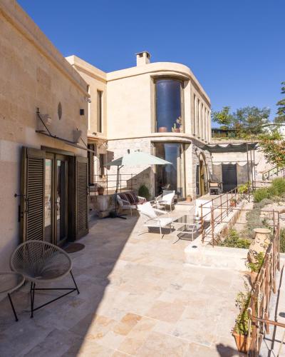 a patio with chairs and tables and a building at Very Peri Cappadocia - The Lifestyle Luxury Design Hotel in Uchisar