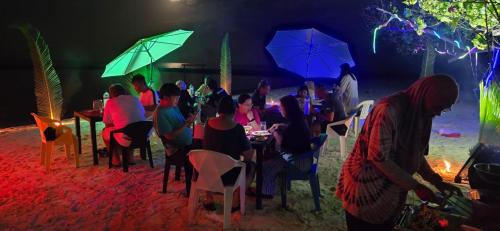 a group of people sitting at tables with umbrellas at Liberty Guesthouse Maldives in Mahibadhoo