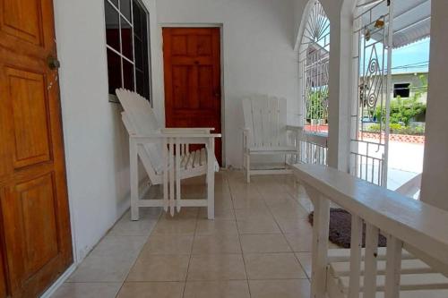 a porch with white chairs and a table and a door at Lovely 2 Bedroom House in St Thomas Jamaica in Belfast