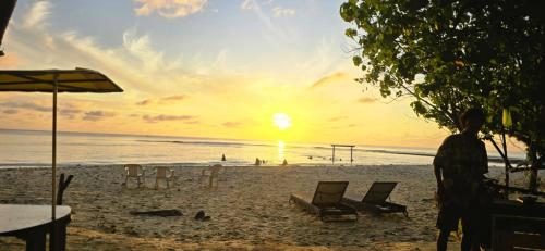 a person standing on a beach with a sunset at Liberty Guesthouse Maldives in Mahibadhoo