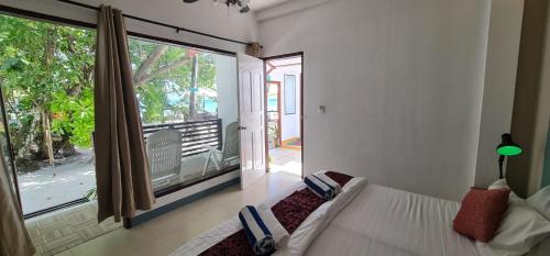a bedroom with a bed and a large window at Liberty Guesthouse Maldives in Mahibadhoo