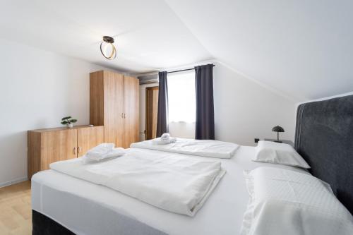 a bedroom with two beds with white sheets and a window at Villa Ema in Bilje