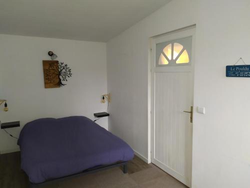 Habitación con cama y puerta con ventana en Gîte Ty Laouen Clohars-Carnoët, en Clohars-Carnoët