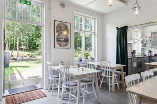a kitchen and dining room with tables and chairs and windows at STF Villa Söderåsen B&B in Röstånga