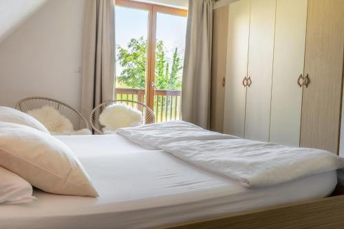 a bed with white sheets and a window in a room at Apartment Rosemary in Topolšica