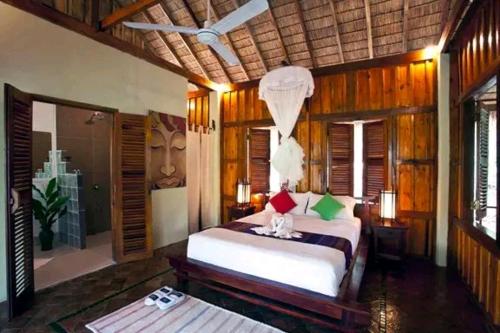 a bedroom with a bed in a room with wooden walls at Zen Namkhan Boutique Resort in Ban Xianglôm